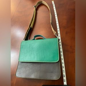 Leather color block shoulder bag with short handle and adjustable leather strap.